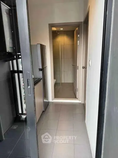 Compact modern kitchen with sleek appliances and adjacent bathroom in urban apartment.