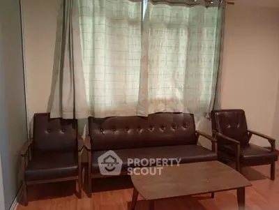 Cozy living room with classic leather furniture and wooden coffee table, perfect for relaxation.