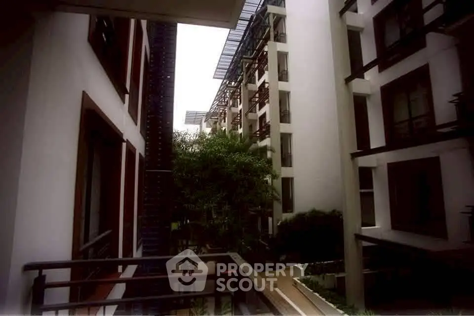 Modern apartment building exterior with lush greenery and sleek architectural design.