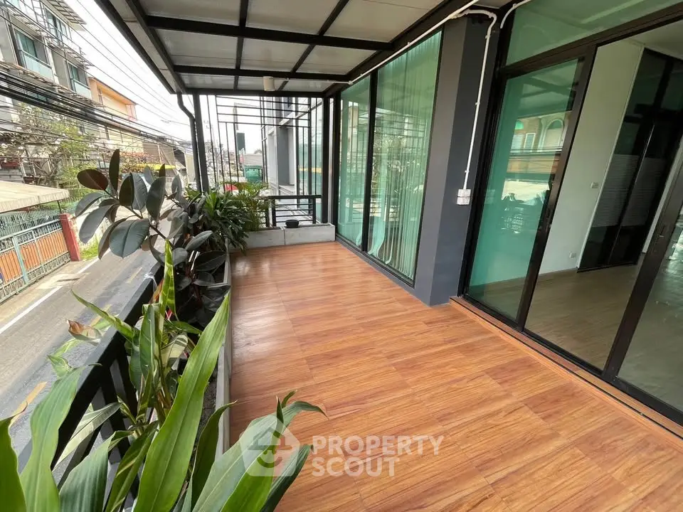 Spacious balcony with wooden flooring and lush plants, perfect for relaxation and enjoying city views.