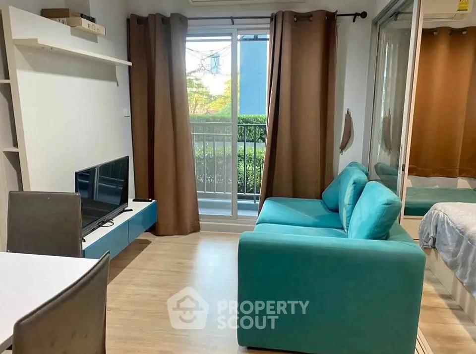 Cozy living room with teal sofa and balcony view, perfect for relaxation.