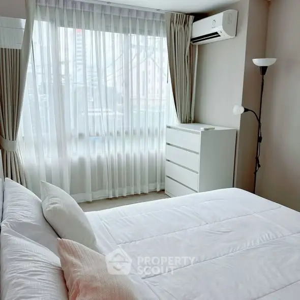 Bright and airy bedroom with large window and modern furnishings.