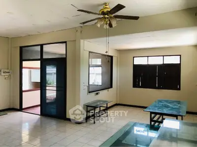 Spacious living room with ceiling fan and large windows for natural light.