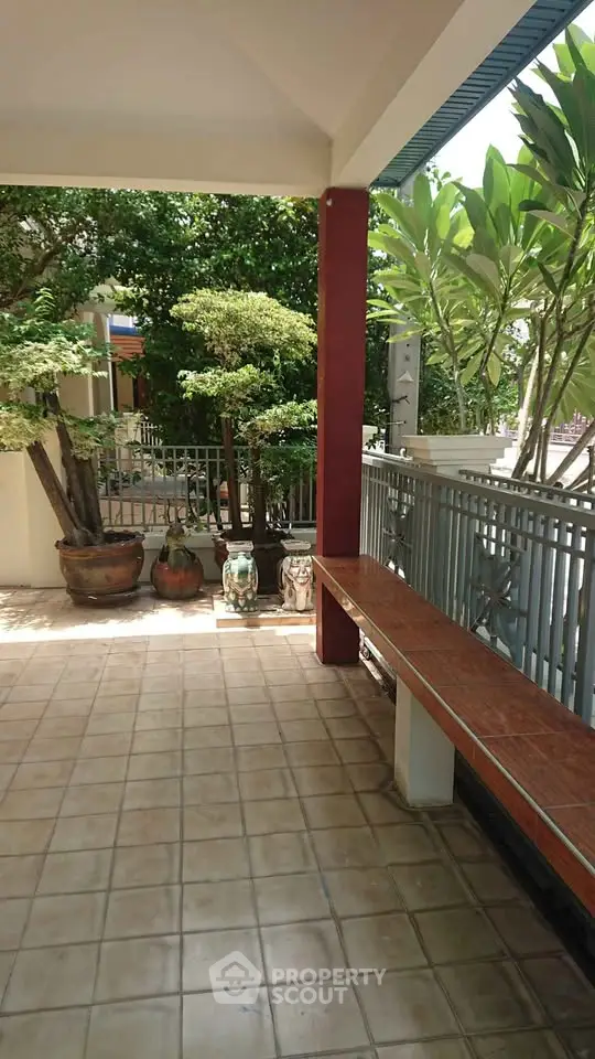 Charming garden patio with lush greenery and tiled flooring, perfect for relaxation.