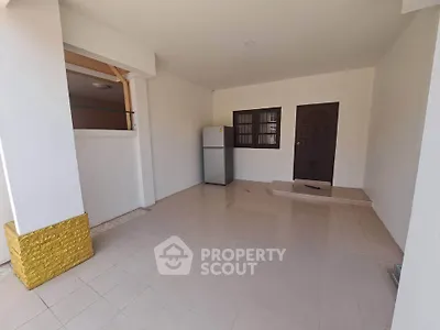 Spacious tiled entrance area with fridge and door, ideal for versatile use.