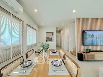 Modern dining area with elegant table setting and wall-mounted TV in stylish living space.