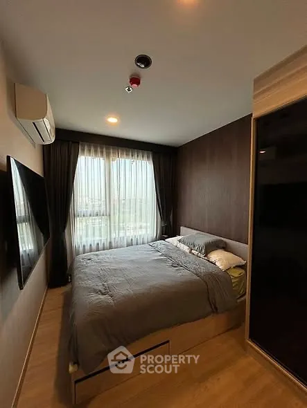 Cozy bedroom with modern decor, large window, and wall-mounted TV in a stylish apartment.