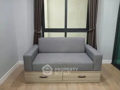 Modern living room with stylish gray sofa and large window view.