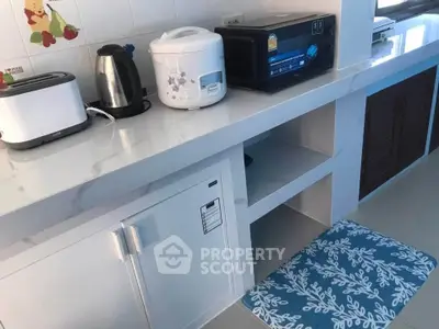 Modern kitchen with appliances including rice cooker and toaster on sleek countertop.