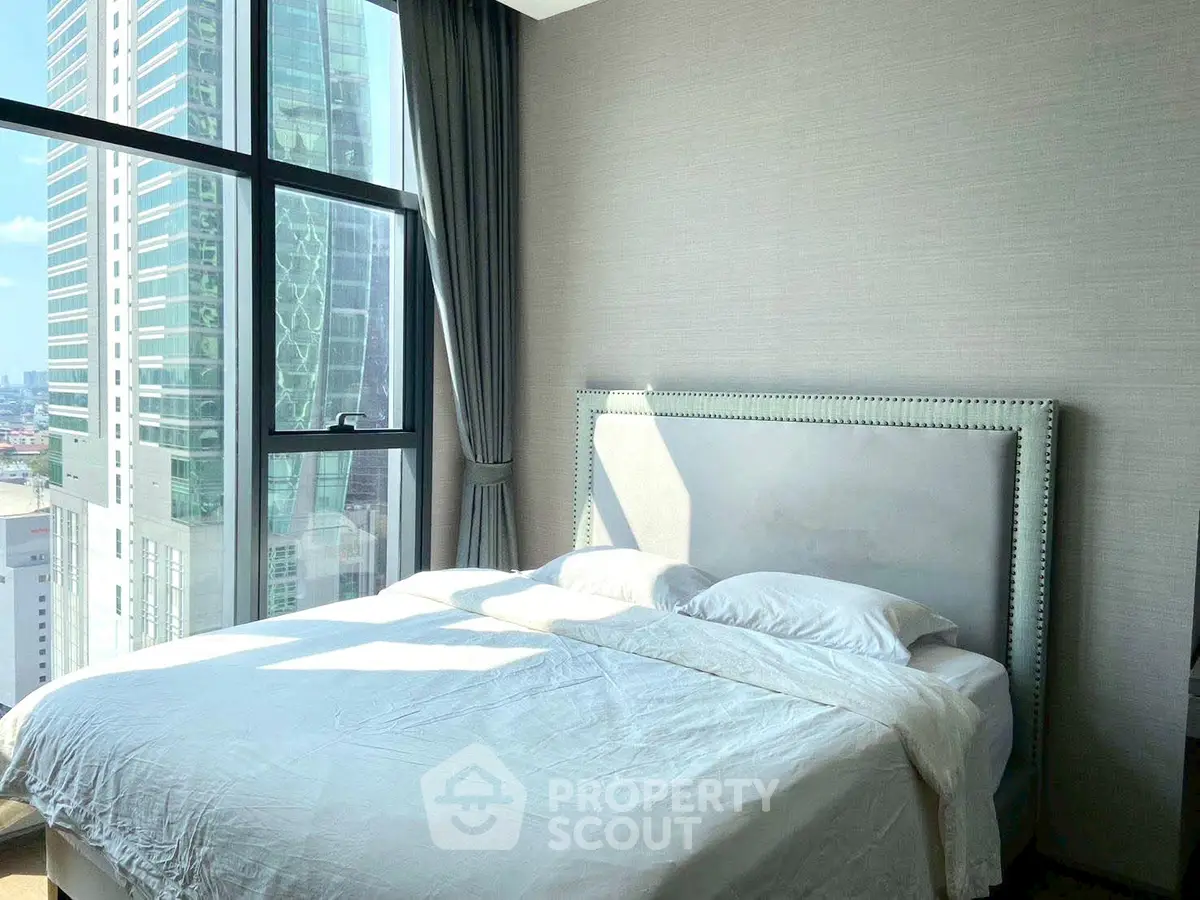 Luxurious bedroom with stunning city view and elegant decor in high-rise apartment.