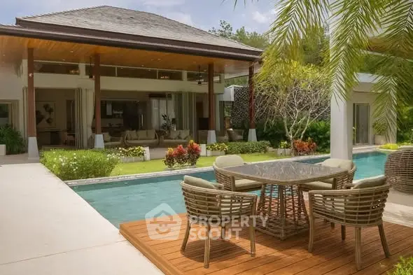 Luxurious villa with poolside dining area and lush garden, perfect for relaxation and entertaining.