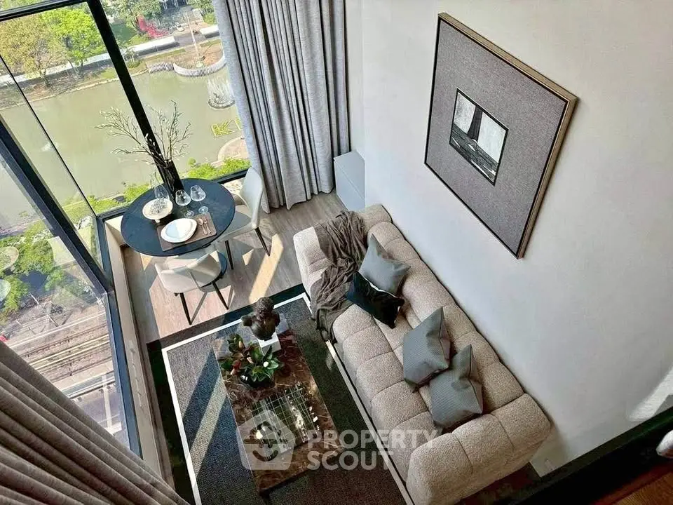Modern living room with large windows and scenic view, featuring stylish decor and cozy seating area.