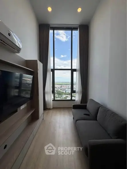 Modern living room with high ceiling and stunning city view through large window.