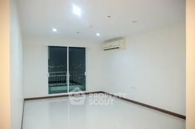 Spacious unfurnished living room with balcony and city view, featuring modern air conditioning.