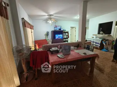 Spacious living room with dining area and TV, featuring cozy furnishings and natural light.