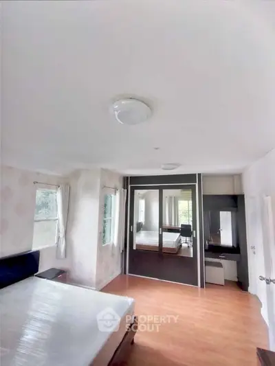 Spacious bedroom with large mirrored wardrobe and natural light