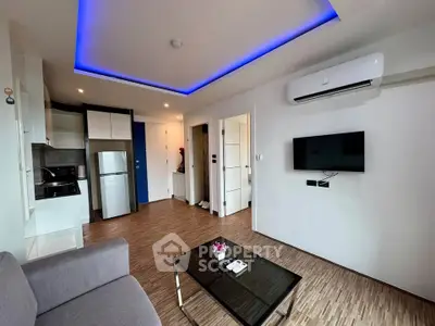 Modern living room with sleek design, featuring LED ceiling lights, air conditioning, and compact kitchen area.