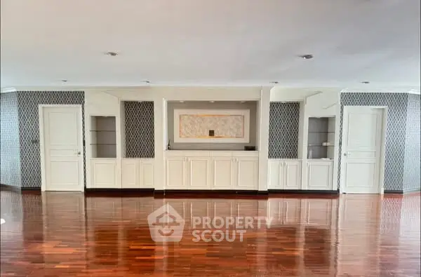 Spacious living room with elegant wooden flooring and built-in shelving