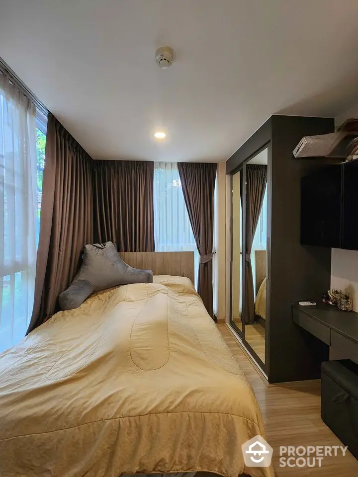 Cozy bedroom with large windows and modern furnishings in a stylish apartment.