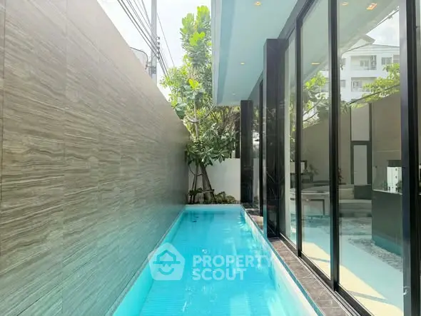 Luxurious private pool with modern glass wall and lush greenery, perfect for relaxation and entertainment.