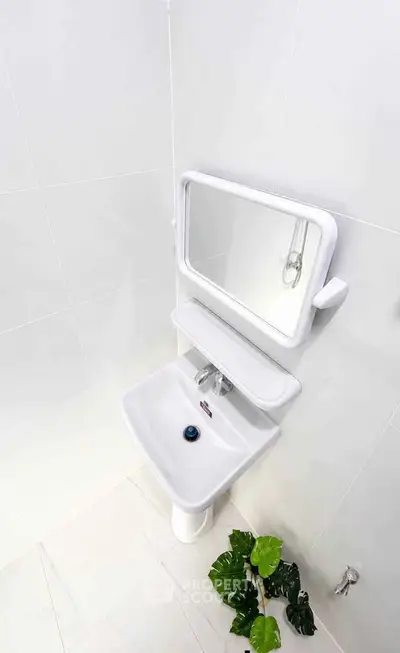 Modern bathroom with sleek white sink and mirror, minimalistic design