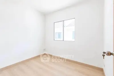 Bright empty room with wooden flooring and window, perfect for customization.