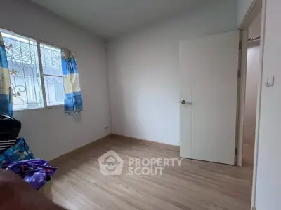 Spacious bedroom with wooden flooring and natural light from window