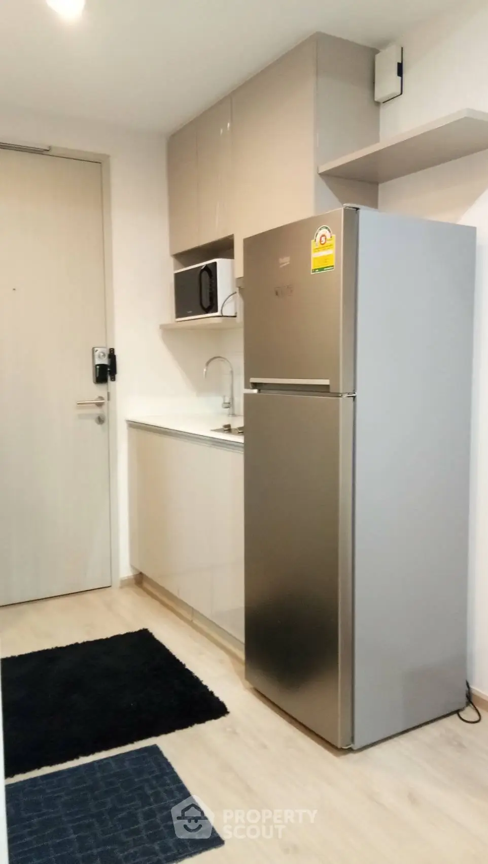 Modern compact kitchen with stainless steel fridge and sleek cabinetry
