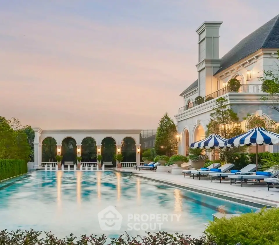 Luxurious estate with grand pool and elegant architecture at sunset.