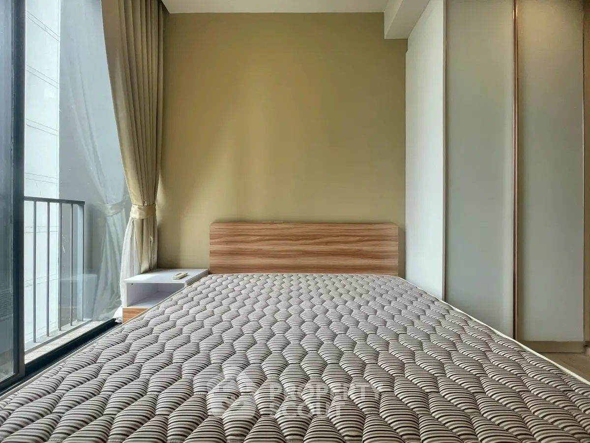 Modern bedroom with large window and minimalist design, featuring a comfortable bed and neutral tones.