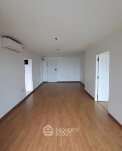 Spacious empty room with wooden flooring and white walls, ideal for customization.