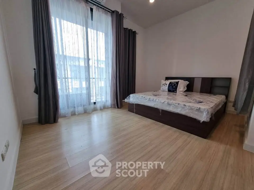 Spacious bedroom with large window and modern decor, perfect for relaxation and comfort.
