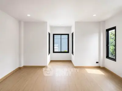 Spacious empty room with large windows and wooden flooring, perfect for customization.
