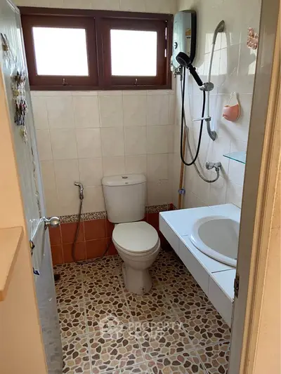 Compact bathroom with modern fixtures and natural light from small windows.