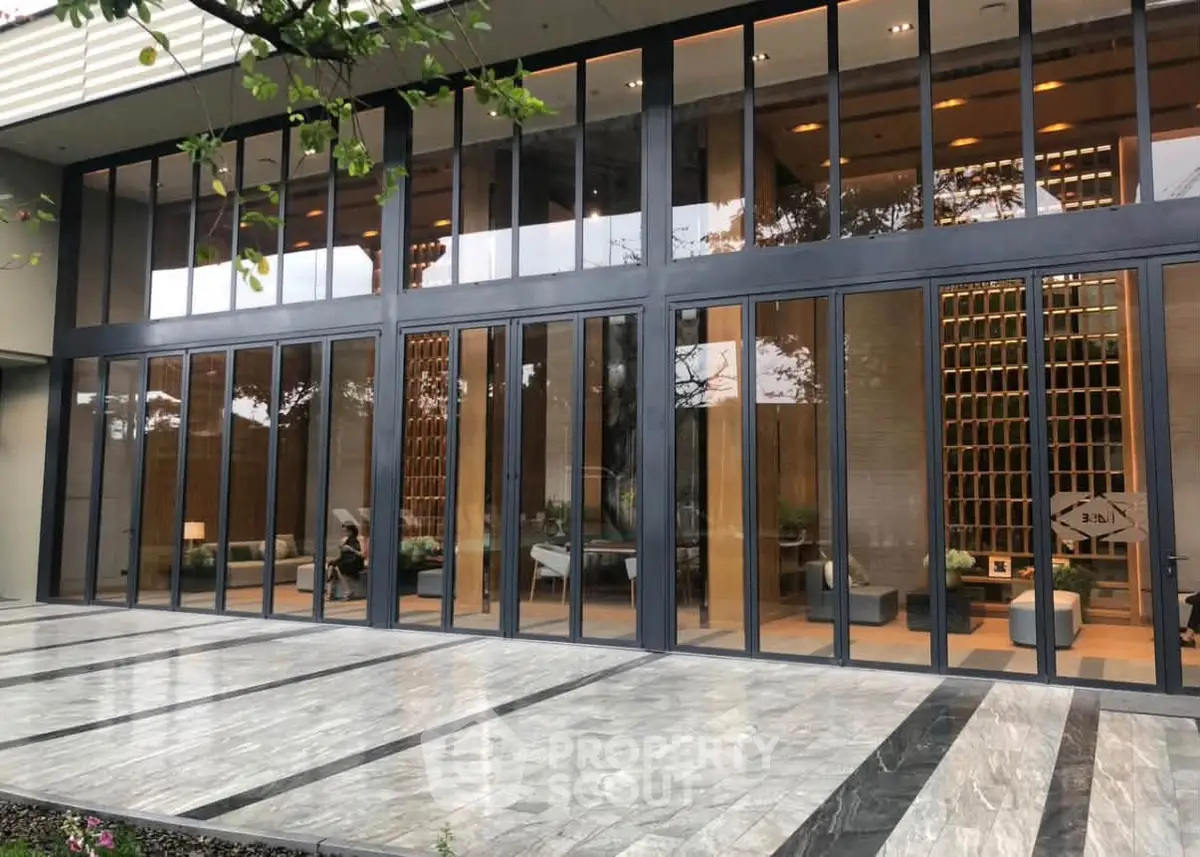 Luxurious building entrance with floor-to-ceiling glass windows and elegant marble flooring.