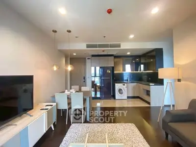 Modern open-plan living room with kitchen and dining area, featuring stylish furniture and appliances.