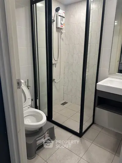 Modern bathroom with glass shower enclosure and sleek fixtures in a contemporary apartment.