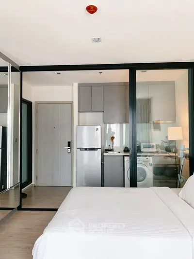 Modern studio apartment with compact kitchen and cozy bedroom area, featuring sleek appliances and stylish decor.
