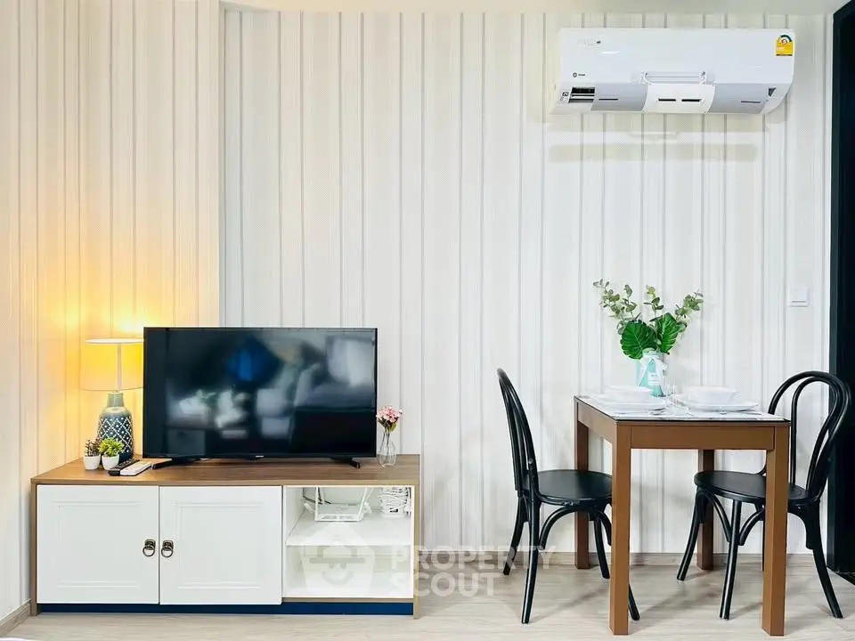 Modern living room with TV, dining table, and air conditioning in stylish apartment.