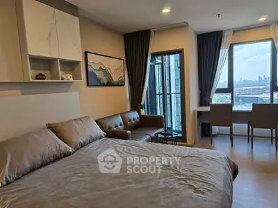 Modern bedroom with city view, stylish decor, and cozy seating area.