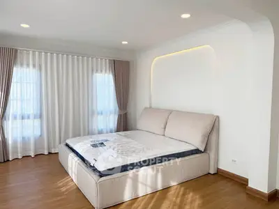 Spacious bedroom with elegant design and natural light, featuring a large bed and stylish curtains.