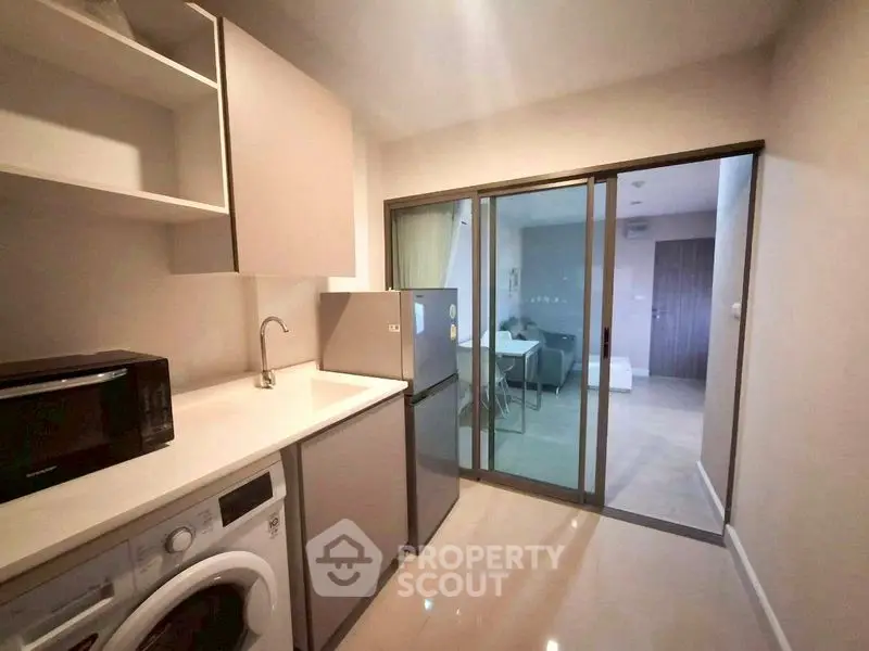 Modern kitchen with washing machine and fridge in sleek apartment
