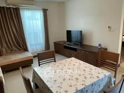 Cozy living room with dining area, featuring a TV and elegant curtains.