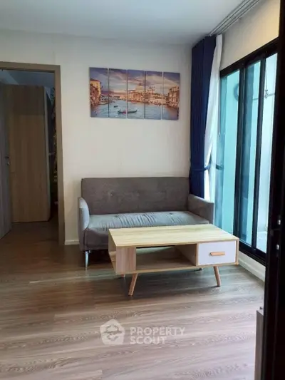 Modern living room with stylish sofa and wooden coffee table, featuring large windows for natural light.