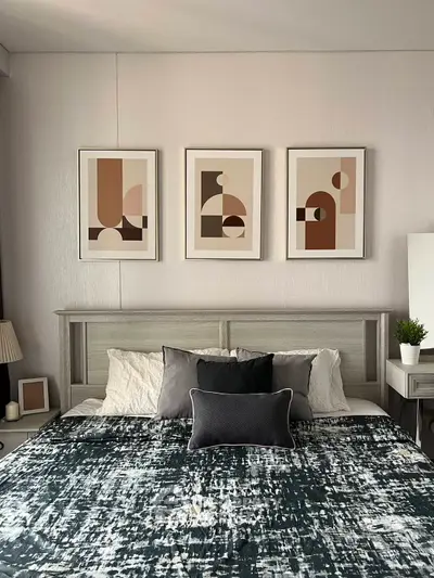 Stylish bedroom with modern decor and abstract art above the bed, creating a cozy and inviting atmosphere.