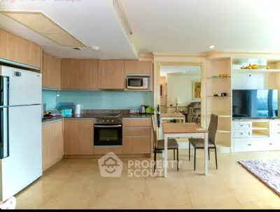 Modern open-layout kitchen with dining area and living room, featuring sleek appliances and stylish decor.