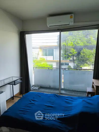 Cozy bedroom with balcony view and air conditioning in modern apartment.