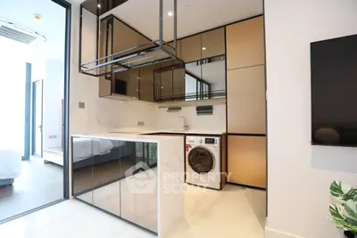 Modern kitchen with sleek cabinets and built-in washing machine in luxury apartment.