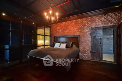 Stunning industrial-style bedroom with exposed brick and elegant chandelier.