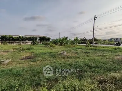 Spacious green plot of land with potential for development, surrounded by lush vegetation and clear skies.
